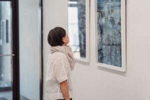 Frau betrachtet konzentriert ein gerahmtes Kunstwerk im Ausstellungsraum