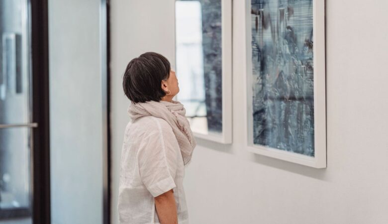 Frau betrachtet konzentriert ein gerahmtes Kunstwerk im Ausstellungsraum