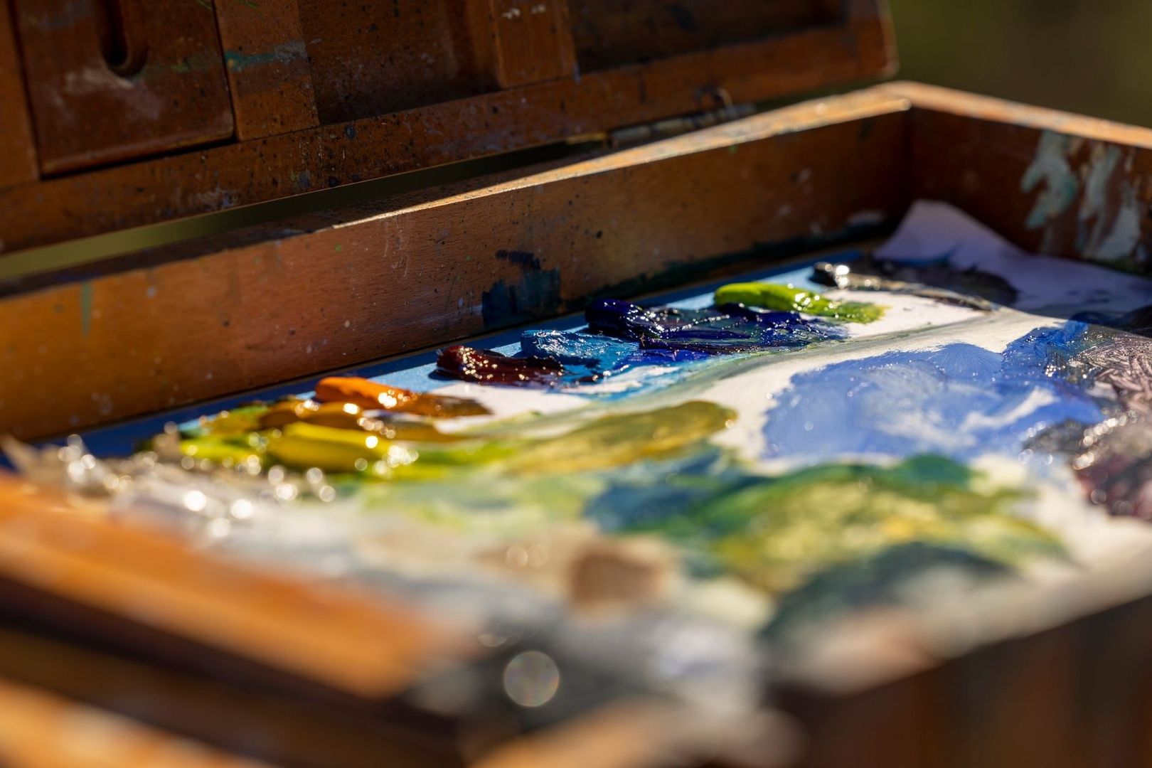 Nahaufnahme einer Palette mit glänzenden Farben in einer Holzkiste